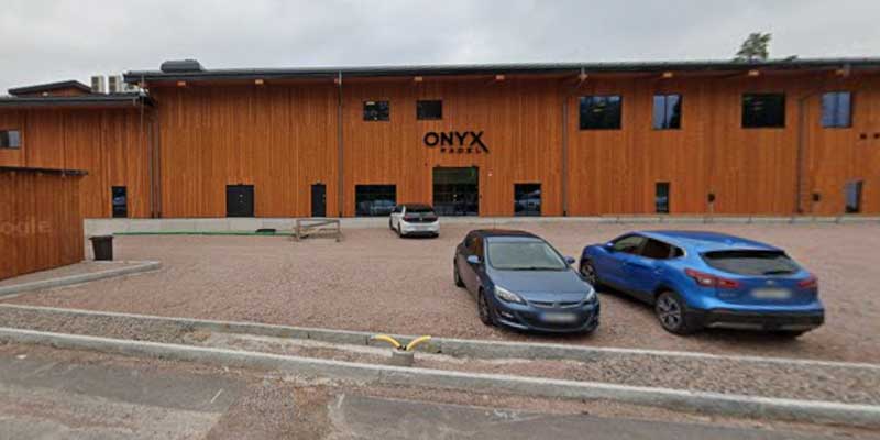 Träklädd padelhall med skylten Onyx Padel och parkerade bilar framför entrén